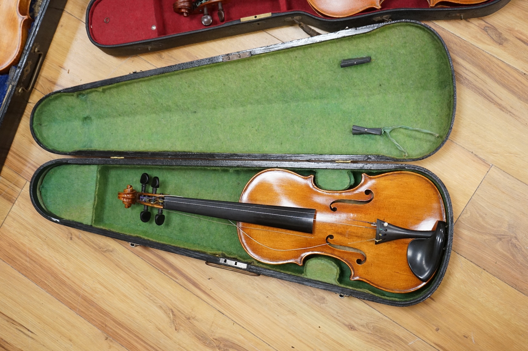 Three violins; a late 19th century German Stradivarius pattern violin, without label, a handmade violin (a.f.), with sound post crack, broken and repaired scroll, etc. and a Maidstone violin body, varnish stripped from t